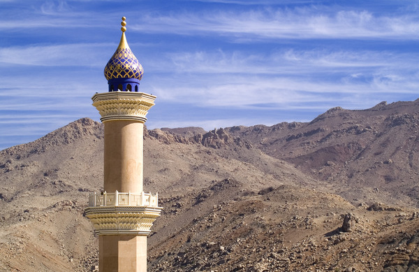 Mosque minaret with rocky desert mountains around Nizwa, Oman